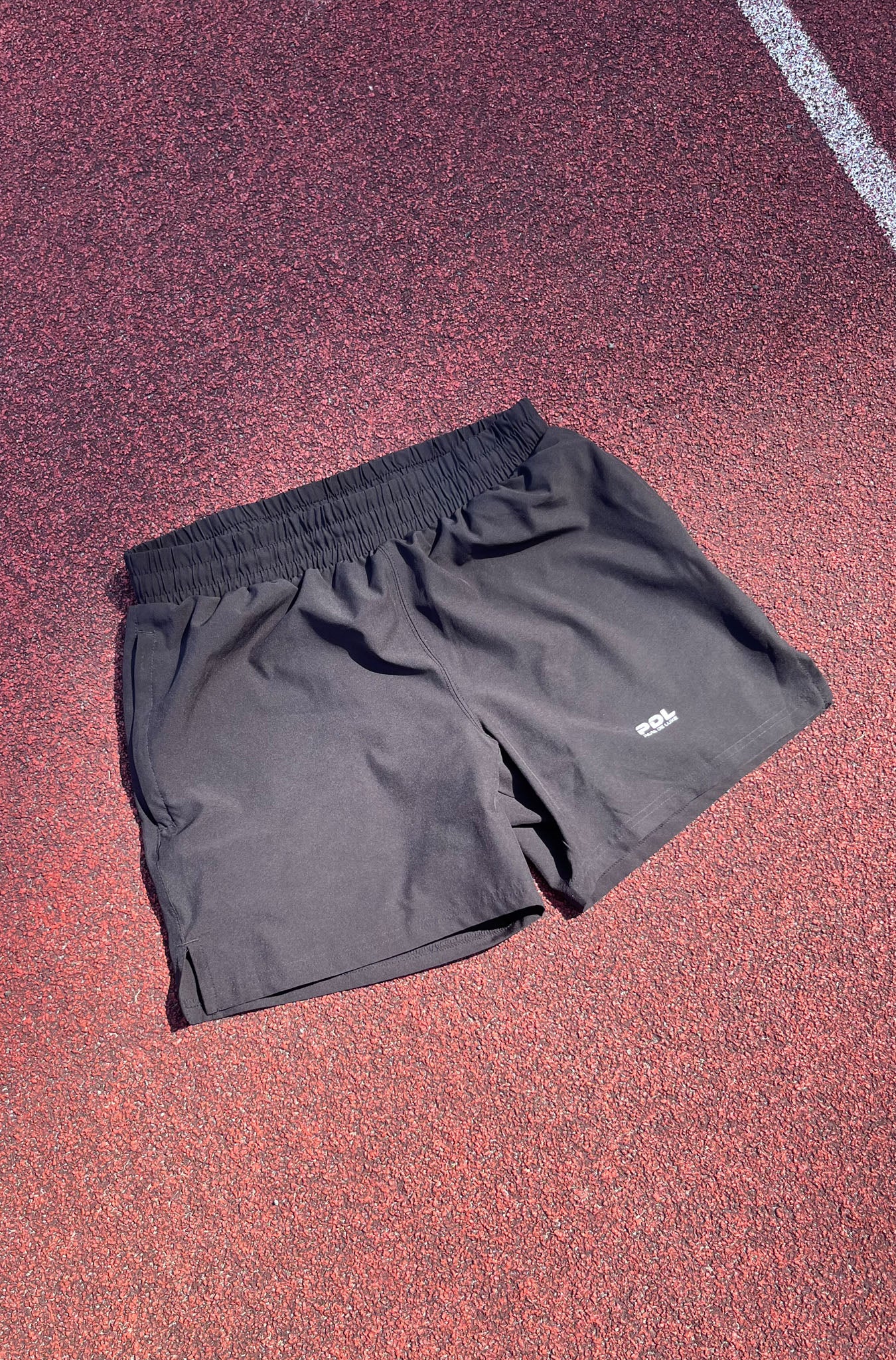 Black shorts with a brand logo on a red track surface