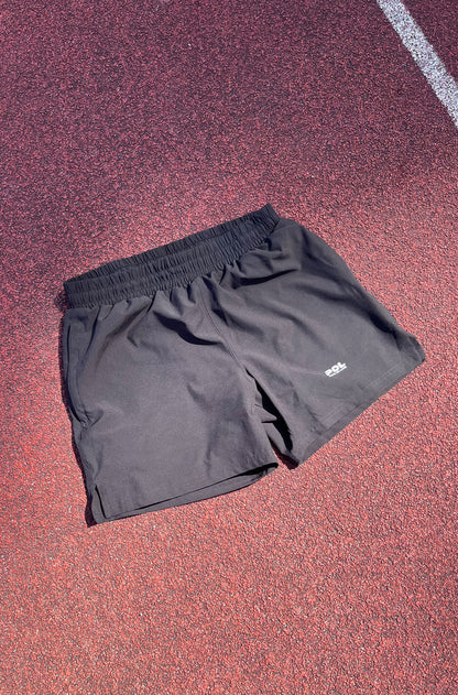 Black shorts with a brand logo on a red track surface