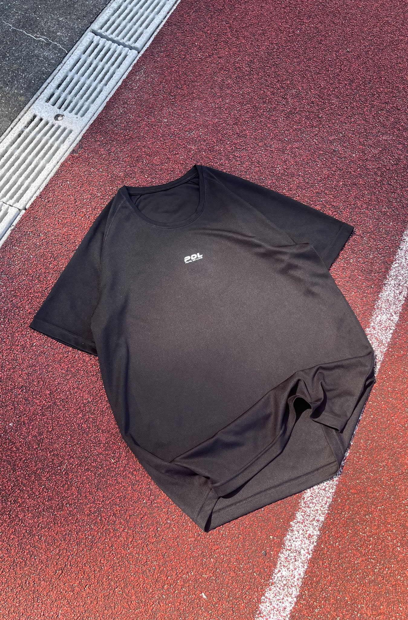 Black t-shirt with a logo on a red and gray surface