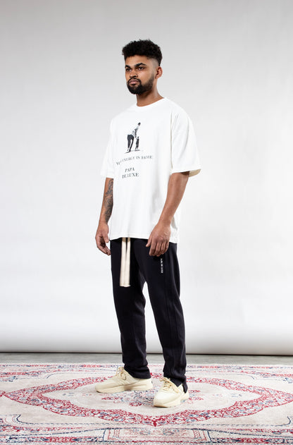 Man wearing Papa De Luxe 'Your Energy Is Home' white graphic T-shirt side view showing relaxed silhouette and drape.